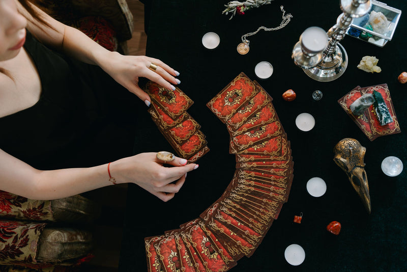 Tirage de tarot sur une table sombre avec bougies, consultation de voyance